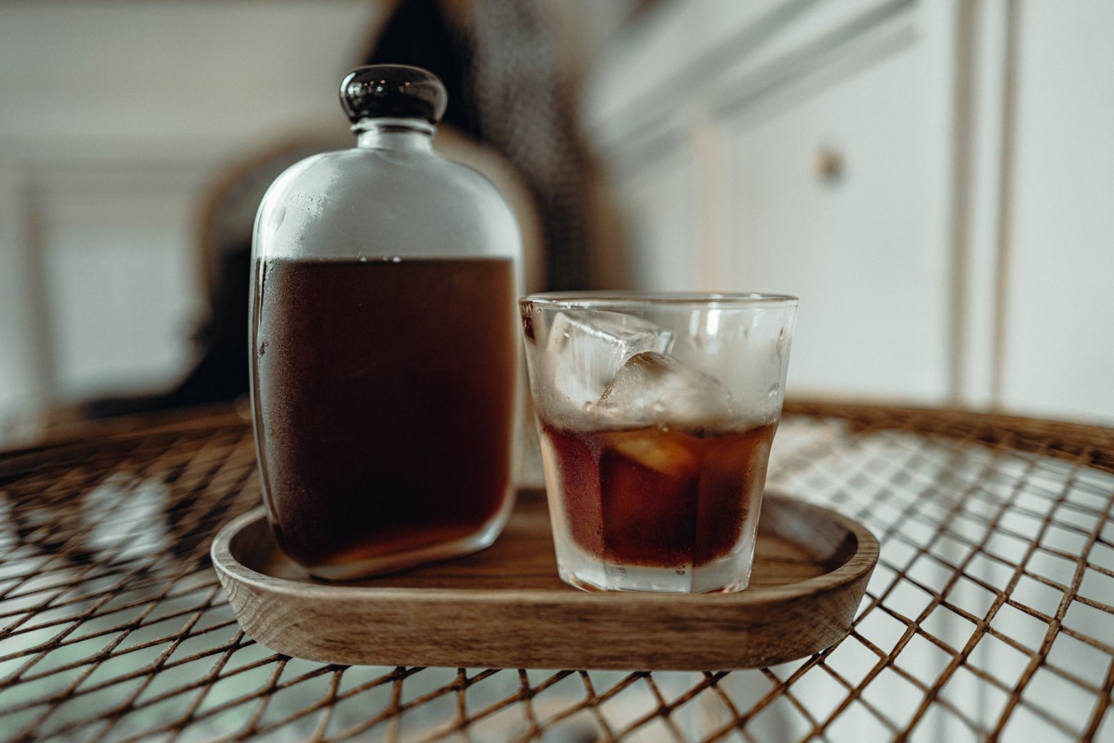 Bottle of cold brew coffee and a glass of iced coffee on a wooden tray
