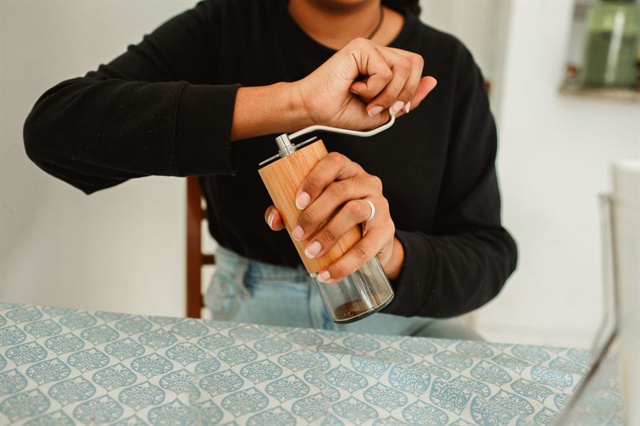 Person turning the handle of a wooden hand grinder