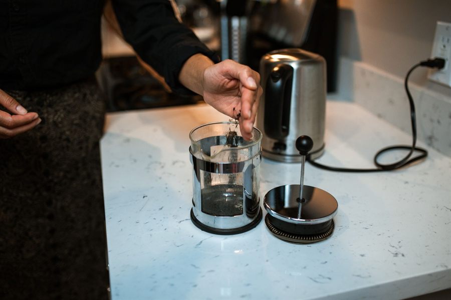 Hand lowering the plunger lid onto a glass French press